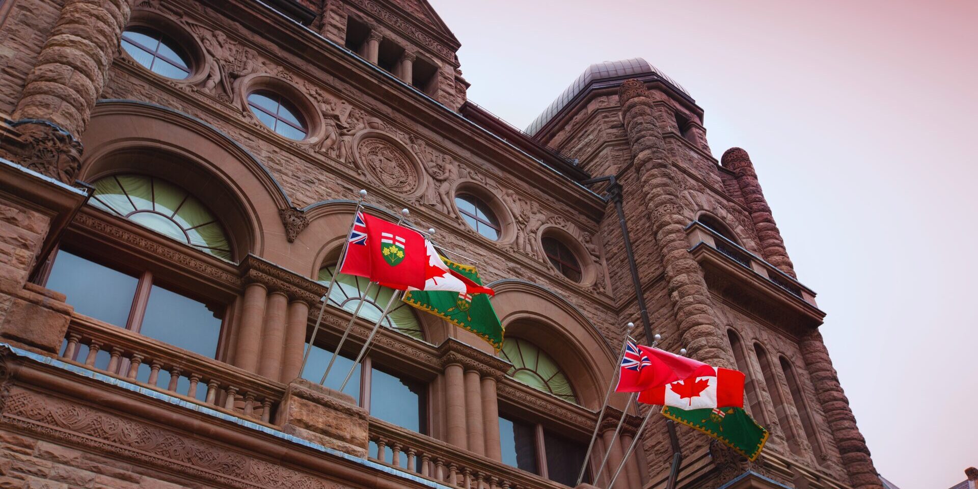 Ontario legislative building with Canadian and Ontario flags waiving out front